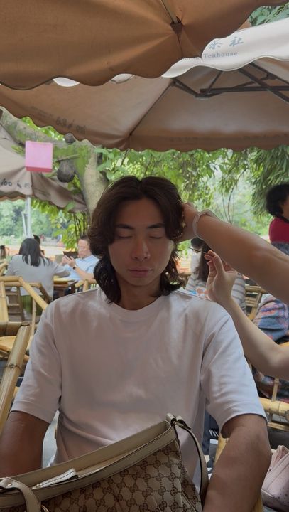 A traveller with his eyes closed having his ears cleaned in a Chengdu teahouse