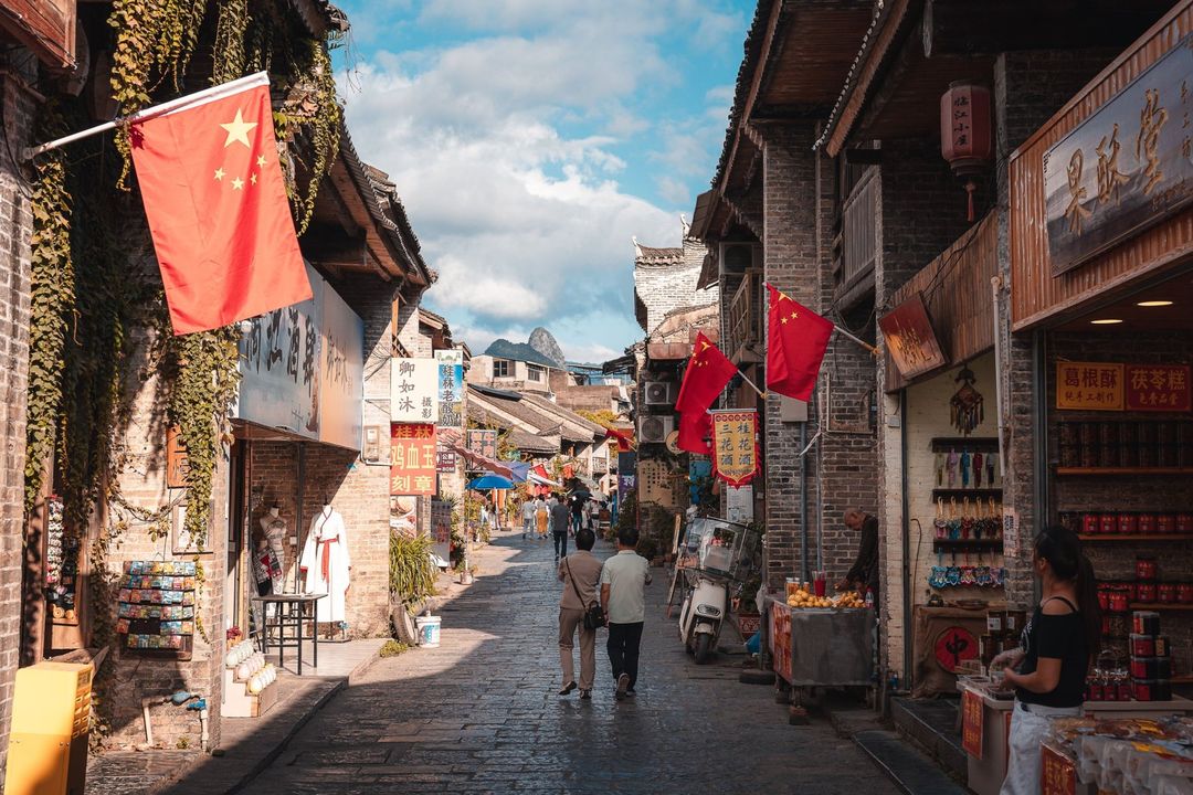 An old-town street with red flags and shopfronts