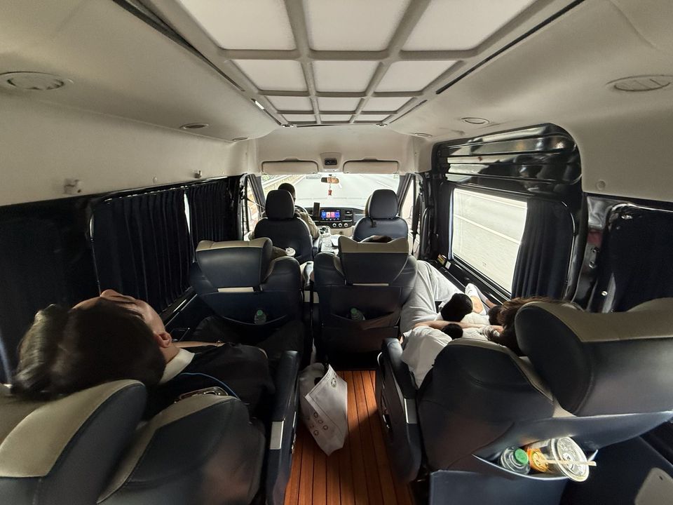 The inside of a private van, seats reclined, curtains drawn