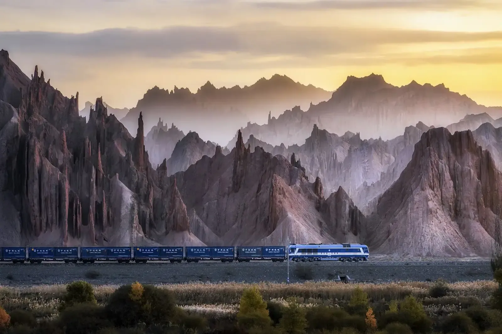 Train travelling beneath rugged mountains in Xinjiang