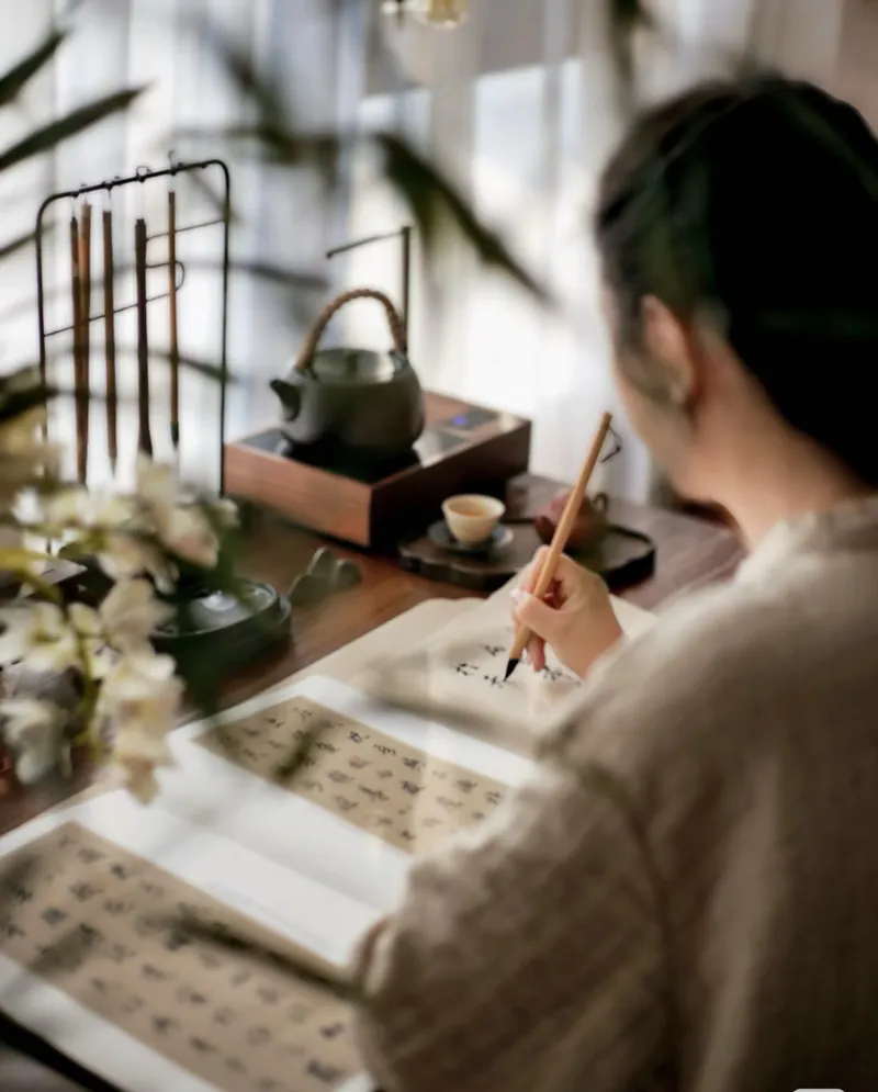 Traveller practising Chinese brush calligraphy at a tea table