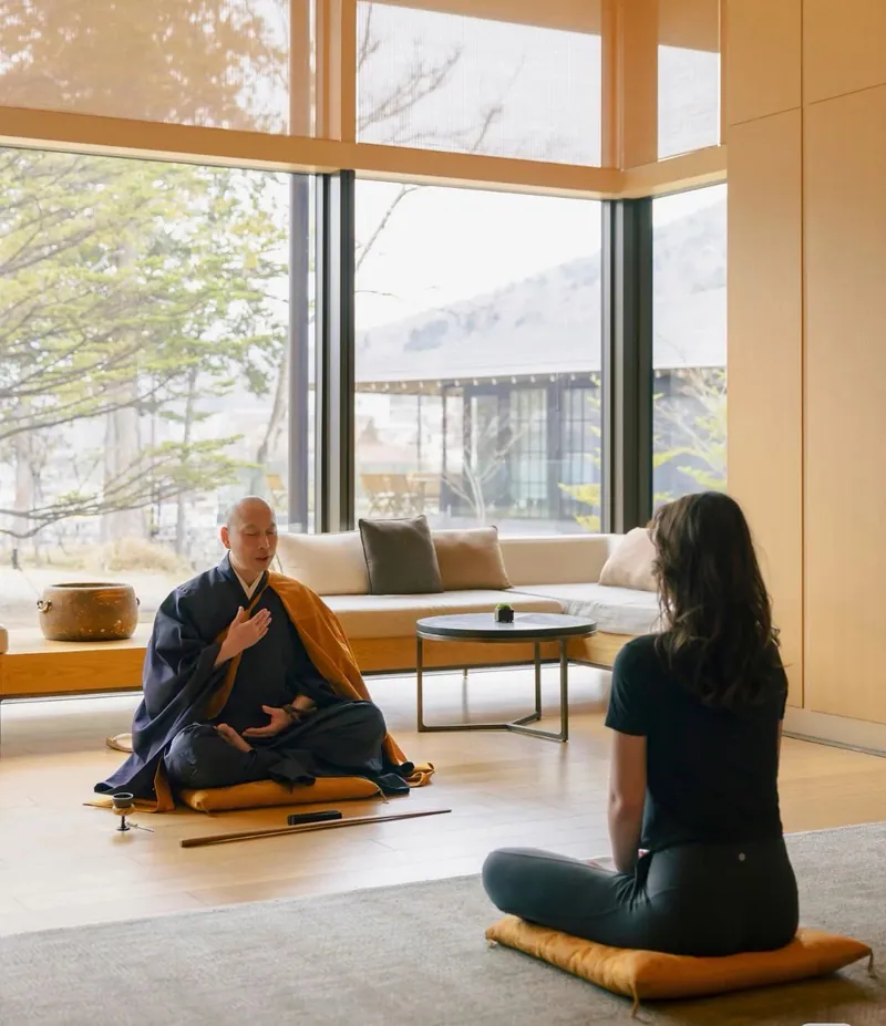 Traveller meditating with a Buddhist monk indoors