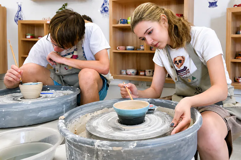 Travellers painting ceramic bowls in a pottery studio